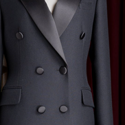 Close-up of women's long double-breasted black coat with satin lapels and matte buttons, showcasing luxurious tailoring and elegant design.