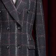 Close-up of women's double-breasted plaid overcoat in black with red and white accents. Sustainable, eco-friendly design for sophisticated formal style.