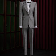 Women's tailored Black and White Pattern Suit, featuring structured shoulders, fitted waist, and white blouse with black ribbon, exuding vintage elegance.