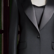 Close-up of women's black tuxedo suit with satin lapels and single-button closure, highlighting luxury tailoring and sophisticated design for formal events