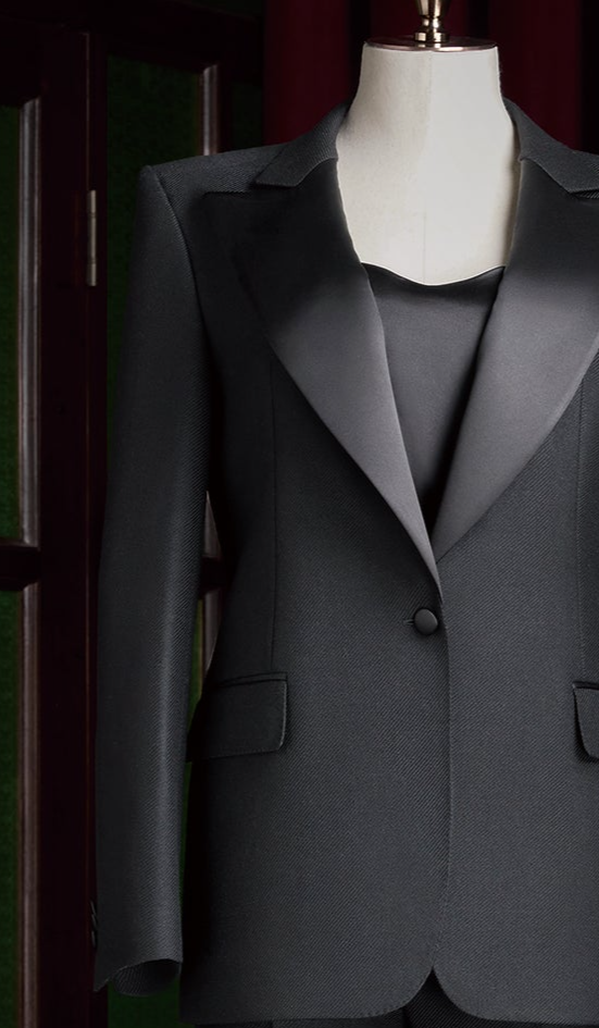 Close-up of women's black tuxedo suit with satin lapels and single-button closure, highlighting luxury tailoring and sophisticated design for formal events
