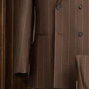 Close-up view of an elegant brown pinstripe men's suit jacket featuring a double-breasted design, showcasing fine tailoring and sophisticated style for formal occasions.