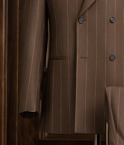 Close-up view of an elegant brown pinstripe men's suit jacket featuring a double-breasted design, showcasing fine tailoring and sophisticated style for formal occasions.