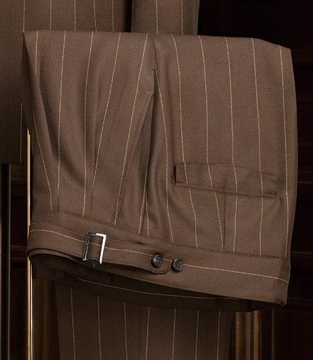 Close-up of brown pinstripe tailored trousers with adjustable side tabs, showcasing fine craftsmanship and sophisticated detailing, ideal for formal wear.