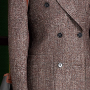 Close-up of women's brown tweed blazer with double-breasted design, showcasing textured fabric and structured tailoring for a sophisticated, eco-friendly style.