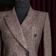 Close-up of women's brown tweed blazer with double-breasted design and peak lapels, showcasing high-end tailoring and textured fabric detail. Perfect for formal, eco-conscious style.