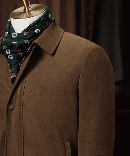 Close-up of brown button-up jacket collar for men, paired with a patterned green scarf, showcasing fine tailoring and luxurious, eco-friendly materials.