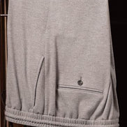 Close-up of tailored grey pants with elasticized waistband and sleek back pocket detail, crafted from sustainable fabric for premium comfort and style.