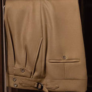 Close-up of camel tailored trousers with adjustable side tabs and buttoned pockets, crafted from premium sustainable fabric for a refined, eco-conscious style