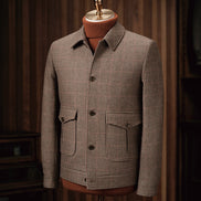 Close-up of a tailored houndstooth field jacket on a mannequin, showcasing fine detailing, sustainable fabric, and classic pockets, ideal for formal wear.