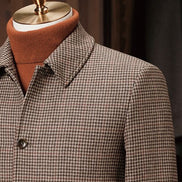Close-up of houndstooth field jacket collar and shoulder, showcasing fine tailoring, sustainable fabric, and classic design, perfect for a sophisticated look.