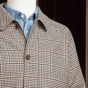 Close-up of houndstooth sports coat collar and shoulder paired with a blue shirt, showcasing sustainable fabric and tailored elegance for formal occasions.
