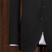 Close-up of tailored suit sleeve with buttons, highlighting fine stitching and sustainable craftsmanship for a refined, formal look.