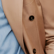 Close-up of soft beige double-breasted suit buttons and pocket, highlighting refined tailoring and luxurious fabric, ideal for an elegant, formal look.
