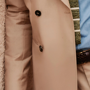 Close-up of beige suit jacket buttons and sleeve, showcasing detailed craftsmanship and smooth fabric, perfect for eco-conscious, high-end fashion.