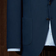 Close-up of expertly crafted buttons and pockets on a navy suit jacket, designed for women seeking high-end, sustainable formalwear with a touch of sophistication