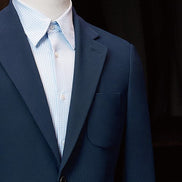 Detailed view of peak lapels and chest pocket on a classic navy suit jacket, showcasing fine tailoring and luxury fabric for a refined and sustainable style.