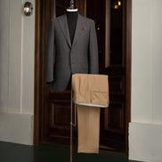Displayed on a mannequin, this formal outfit includes a dark grey checked jacket and beige trousers, exuding elegance and high-end style.