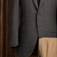  A luxurious ensemble featuring a dark grey checked jacket and beige trousers, ideal for formal events with a touch of sophistication.