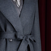 Detailed view of a dark grey overcoat's upper section, highlighting wide lapels and a sophisticated tie-front closure, designed for luxurious warmth and style.