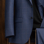 Detailed view of the sleeve and buttons on a deep blue check suit jacket, emphasizing high-quality tailoring and fabric texture.