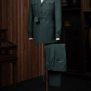 A stylish deep green suit displayed on a mannequin, featuring a belted jacket and formal trousers, perfect for elegant formal events. Made with sustainable materials.