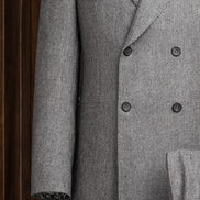 Close-up of a grey double-breasted suit, highlighting textured lined fabric, sleek buttons, and detailed sleeve finish with a patterned shirt cuff for added style.