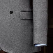 Close-up of a wool double-breasted suit, highlighting textured lined fabric, sleek buttons, and detailed sleeve finish.