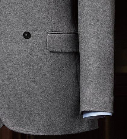 Close-up of a wool double-breasted suit, highlighting textured lined fabric, sleek buttons, and detailed sleeve finish.