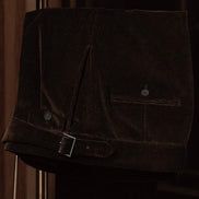 Close-up of brown corduroy trousers with a sleek belt and button details, showcasing refined tailoring and rich texture for a classic men's style