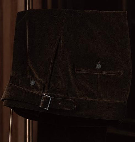 Close-up of brown corduroy trousers with a sleek belt and button details, showcasing refined tailoring and rich texture for a classic men's style