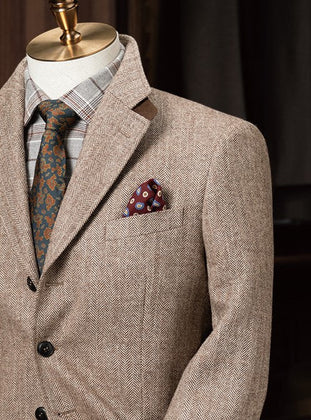 Elegant beige men's tweed blazer on a mannequin with a plaid shirt, floral tie, and pocket square Close up of the pocket square and peak lapels