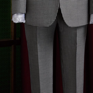 Women's tailored houndstooth suit on mannequin, featuring structured shoulders, fitted waist, and white blouse with black ribbon, exuding vintage elegance. Close up on matching tailored trousers 