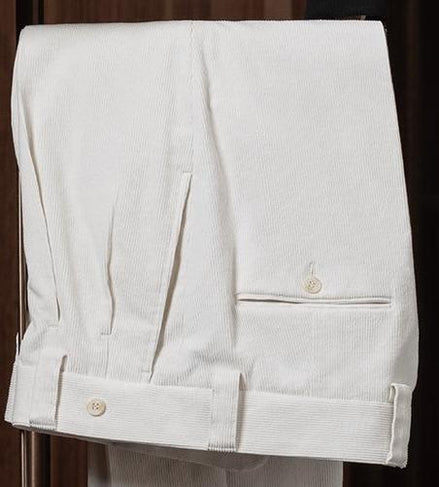 Close-up of cream-colored tailored trousers with cuffed hems and button details, showcasing refined craftsmanship and classic style