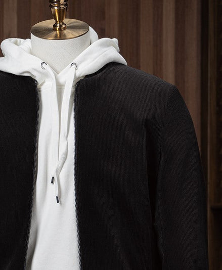 Stylish casual outfit featuring a black tailored zip-up jacket layered over a white hoodie and paired with cream-coloured trousers, displayed on a mannequin for modern streetwear style. Close up on the shoulder stitching 