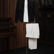 Stylish casual outfit featuring a black tailored zip-up jacket layered over a white hoodie and paired with cream-coloured trousers, displayed on a mannequin for modern streetwear style.