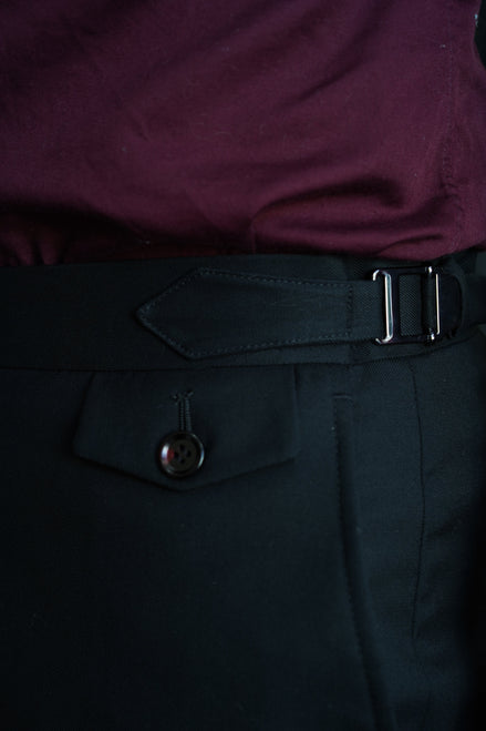 Close-up of men's tailored formal pants with side buckle adjuster and buttoned pocket flap, crafted for a refined and high-end formal look.